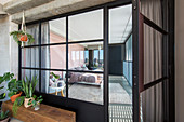 Houseplants on wooden beam next to industrial door leading into living room