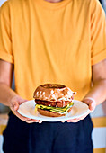 A person holding a Katsu Melt Burger on a plate