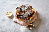 Overhead image of traditional bread pudding with custard, served with aromatic orange zest butter and powdered sugar