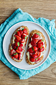 Yummy sweet bread toasts with fresh chopped strawberries and honey served on plate on blue tablecloth