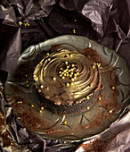 Chocolate cake with cream and golden chips placed against shabby background