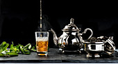 Fresh hot aromatic mint tea being poured into glass cup placed on table