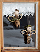 Angels made from fir cones and natural materials hung in window