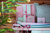 Verpackte Geschenke und Kissen in Rosa und Mintgrün auf einer Bank