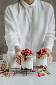 Woman holding a jar of granola yogurt with red currants