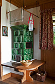 Classic green tiled stove with bench in rustic country house