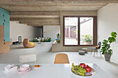 Minimalist, open-plan living room with concrete ceiling and large window overlooking the courtyard