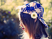 A brunette woman wearing a baseball cap with a flower