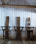 Drei Stühle aus altem Holz vor Bretterwand im Holzhaus