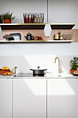 A white kitchen counter with an open shelf above it and pendant lamp hanging from the ceiling