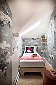 A narrow guest room with a single bed and monochrome wallpaper