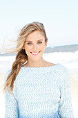 A young woman on a beach wearing a bateau neck jumper