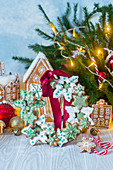 Kranz aus Weihnachtsplätzchen mit Schleife vor Lebkuchenhaus