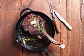 Tomahawk steak in cast iron pan, seasoned with butter and rosemary