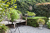 Sitzplatz im Garten mit Bank vor der Efeu bewachsenen Mauer