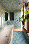 Badewanne mit Holzmaserung im Bad mit Fliesen in Blau und Grün