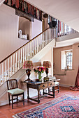 An antique table with chairs against a staircase wall in a entrance area