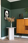Two-tone dark green wall in room decorated in mid-century modern style
