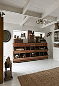 Antiker Holzschrank mit Schubladen und Regalfächern im Zimmer mit weißen Dielenboden