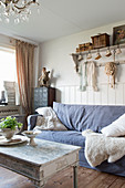 A sofa with a blue cover and a sheepskin in a shabby-chic style living room