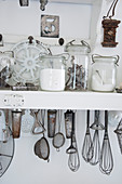 Storage jars and vintage kitchen utensils on a white shelf
