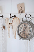 A vintage alarm clock and a pair of wings on hooks