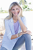 A young blonde woman wearing a purple t-shirt and a blue-and-white striped shirt