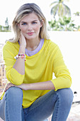Junge blonde Frau in gelbem Pullover und Jeans
