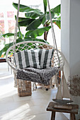 Boat ornament in front of hanging chair with scatter cushions