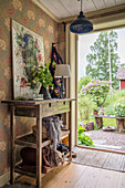 A rustic console table with a picture against a wallpapered wall