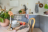 Runder Esstisch aus Holz und Unterschränke mit grauen Fronten in der Küche