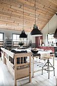 Pendant lights above a dining table with a wooden bench in an open-plan living room