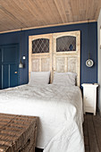 Old doors as a headboard in a bedroom with a blue wall