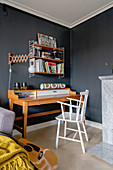 A desk and an open shelf in a guest room with a dark wall