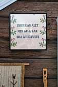 An embroidered picture with message on a rustic wooden wall