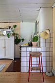 Hocker und Stehlampe vor gefliester Wand in der Küche