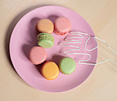Bunte Macarons und Hand aus Draht auf rosa Teller