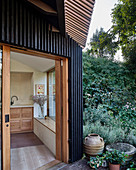Modern extension with open façade structure and open door leading into kitchen