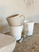 Cups in natural shades on rustic wooden surface next to stone wall