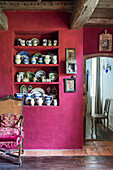Crockery collection in niche in purple wall