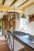 Long counter with gas hob in country house kitchen with wood-beamed ceiling