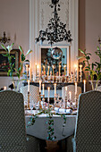 Festively set table below antique copper chandelier and mercury glass candlesticks on mantelpiece