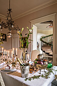 Festlich gedeckter Weihnachtstisch mit Lilie und Quecksilber-Kerzenständern, darüber antiker Kupfer-Kronleuchter