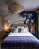 Double bed with bedside cabinets and mural with tree motif in bedroom