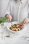 Frau isst Hähnchensalat mit gegrillter Zucchini, Quinoa und Apfel