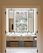 Twin sinks with swivelling mirrors in front of bathroom window