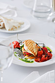 Piece of tasty grilled chicken and cherry tomatoes placed on vegetables on plate in restaurant