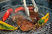 Beef steaks and pointed peppers on a grill