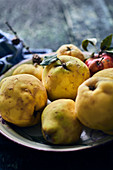 Fresh quinces and apples in an enamel plate