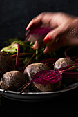 Hand takes fresh beetroot from the plate